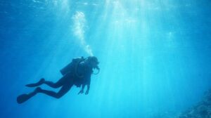 ダイビングで海の中を泳ぐダイバーと差し込む光の水中風景